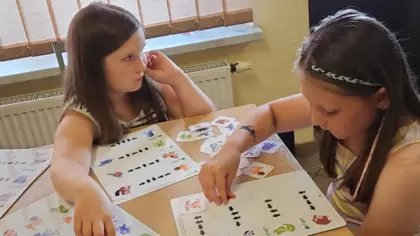 Dwie dziewczynki próbują ułożyć karty ze zwierzątakmi według zawiłego schematu.