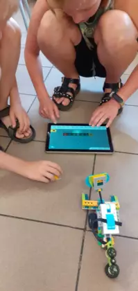 Dzieci tabletem sterują pojazd zbudowany z klocków lego.