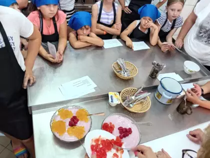 Pani prowadząca pokazuje jak dekoruje szpajze świeżymi owocami i galaretką.