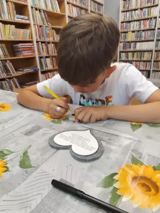 Chłopczyk na serduszku pisze życzenia dla taty.