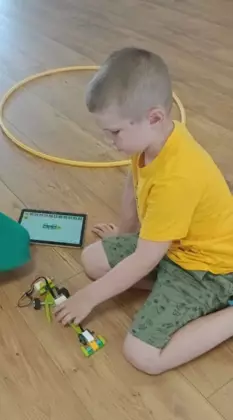 Chłopiec bawi się swoim pojazdem z klocków lego.