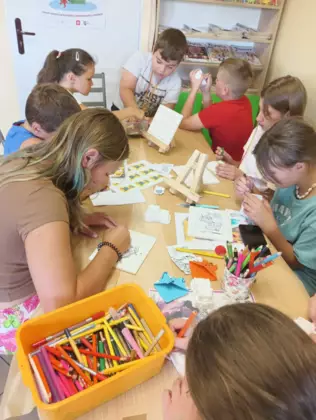 Dzieci kolorują obrazki kolorowymi kredkami.