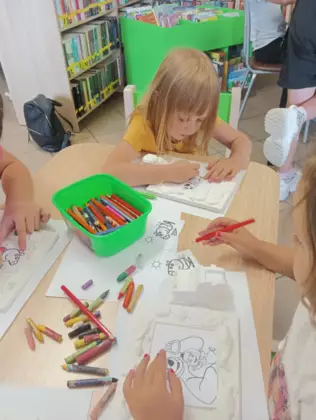 Dzieci kolorują kredkami obrazki.