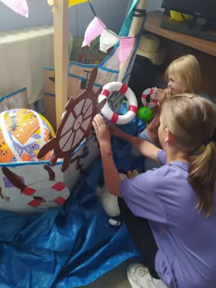 Dwie dziewczynki przyklejają koła ratunkowe do burty statku.