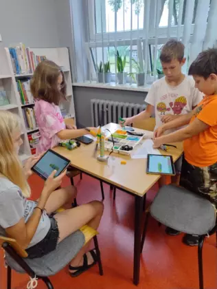 Dzieci budują pojazdy z klocków lego.