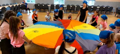 Dzieciaki bawią się kolorowym spadochronem animacyjnym.