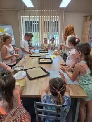 Uczestnicy warsztatów układają jagodzianki na blaszce do pieczenia.