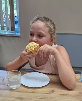 Dziewczynka zjada jagodziankę z posypką.