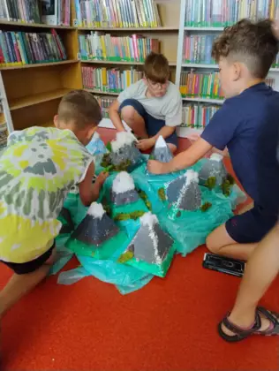 Dzieci tworzą makietę zrobiona ze styropianowych stoków pomalowanych farbami.