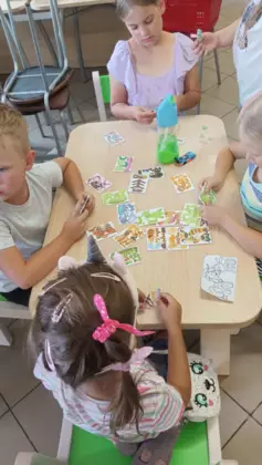 Dzieci siedzą przy stoliku i układają karty.