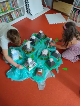 Dzieci tworzą makietę zrobiona ze styropianowych stoków.