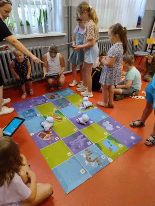 Dzieci kodują roboty na planszach do kodowania.