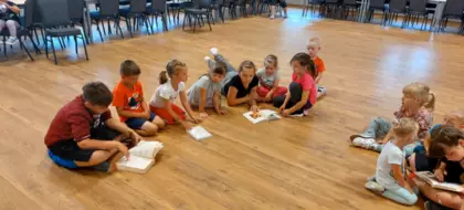 Dzieci siędząc na podłodze przeglądają ksiązki kucharskie.