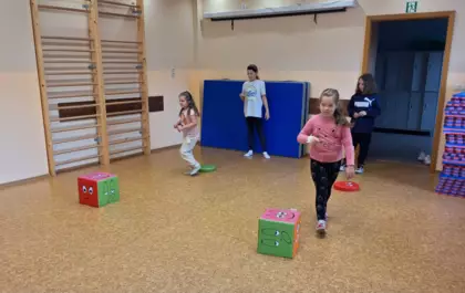 Dzieci bawią się na sali gimnastycznej w tor przeszkód.