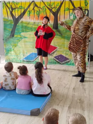 Dzieci siedzą na materacu i oglądają teatrzyk.