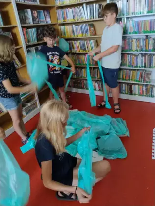 Dzieci tworzą makietę zrobiona ze styropianowych stoków pomalowanych farbami.