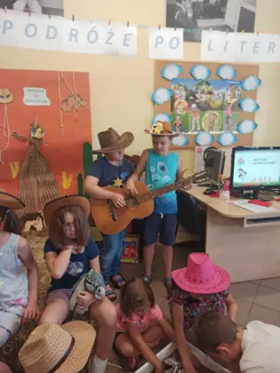 Chłopcy grają na gitarze a dziewczynki wypłukują złoto.