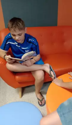 Chłopiec czytający książkę autorstwa Barbary Gawryluk pt. Baster - pies ratownik.