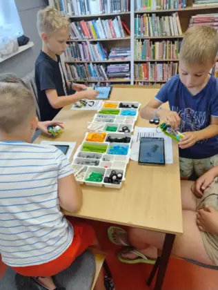 Chłopcy budują z klocków lego pojazdy.