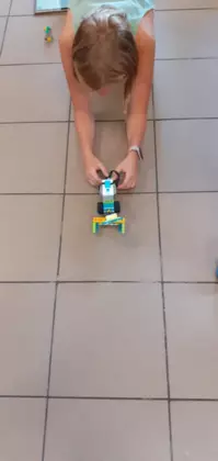 Dziewczynka jedzie pojazdem zbudowanym z klocków lego.