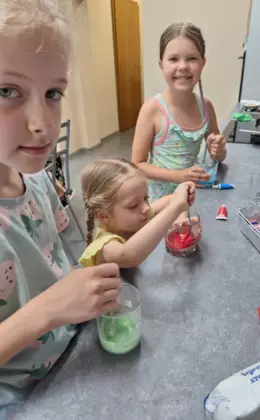 Dziewczynki mieszają kolorowy lukier w szklankach.