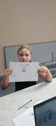 Dziewczyna pokazuje naszkicowany ołówkiem obrazek.