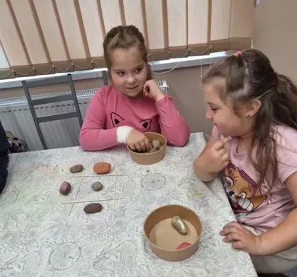 Uczestniczki zajęć grają w grę kółko krzyżyk zrobioną z pomalowanych kamyczków.