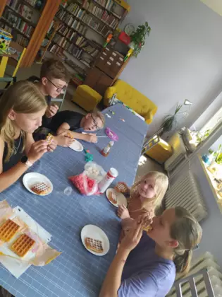 Czas na słodką przekąskę. Dzieci w wolnej chwili zajadają się słodkimi goframi.