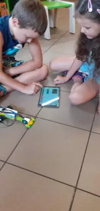 Dzieci tabletem sterują pojazd zbudowany z klocków lego.
