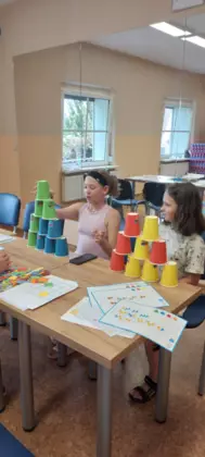 Dziewczynki układają wieżę z kubków.