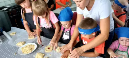 Dzieci nadziewają ciastka drożdżowe (kołoczki) dżemem.