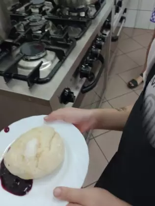 Zdjęcie przedstawia talerz z udekorowaną kluską na parze.