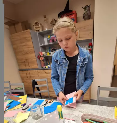 Dziewczynka przykleja małą kopertę do swojej książeczki.