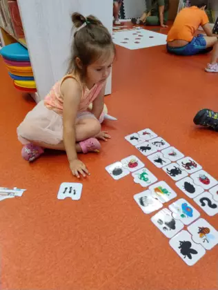 Dziewczynka układa puzzle na podłodze.