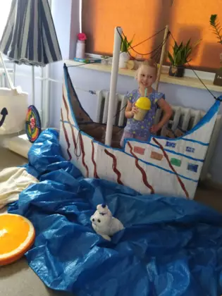 Dziewczynka w statku z kartonu.