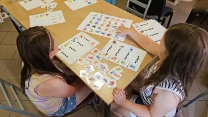Dwie dziewczynki próbują ułożyć karty ze zwierzątakmi według podanego wzoru.