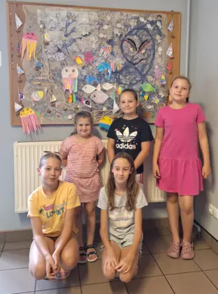 Wspólne zdjęcie zrobione pod obrazem wykonanym przez dzieci.