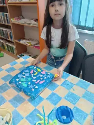 Dziewczynka stoi ze swoją makietą morza.