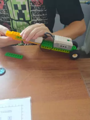 Chłopaka składa samochód z klocków lego.