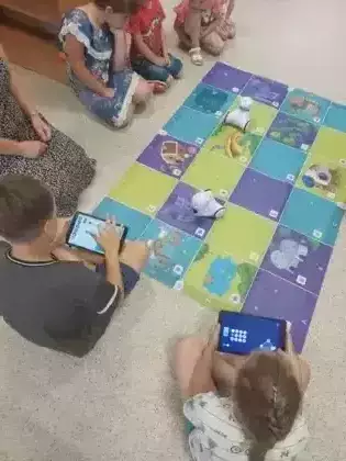 Dzieci programują trasę Photonowi na macie edukacyjnej.