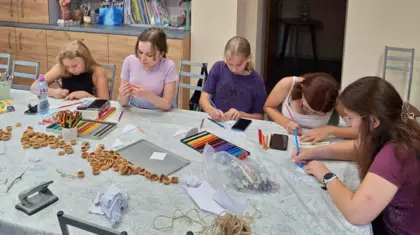 Uczestniczki zajęć kolorowymi kredkami malują żagle łódeczek.