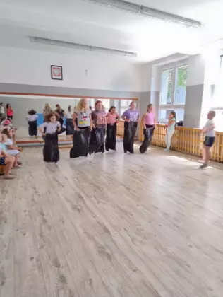 Dzieci skaczą w workach jak kangurki na sali gimnastycznej.