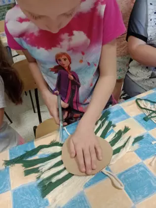 Dziewczynka obcina nadmiar sznurka.