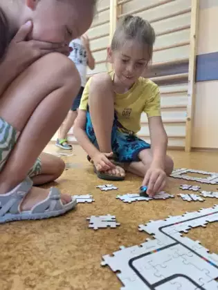 Dziewczynka i chłopczyk bawią się programowaniem Ozobota.