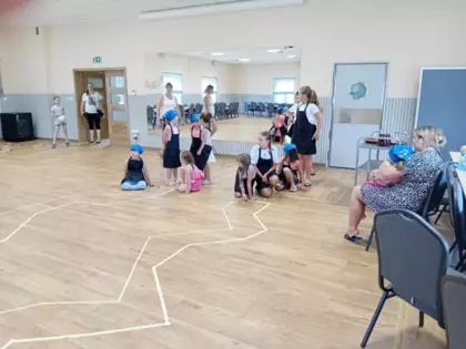 Pani bibliotekarka tłumaczy dzieciom jak grać w kapsle.