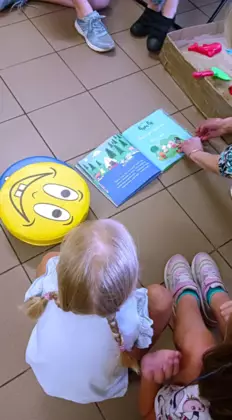 Uczestnicy zajęć słuchają czytanej książeczki.