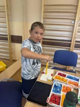 Chłopczyk składa klocki Lego.