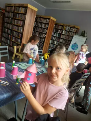 Dziewczynka prezentuje swoją różową kubeczkową rakietę.