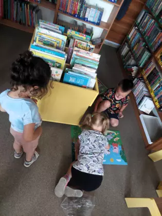 Młodsze dzieci przeglądające wakacyjne książeczki.