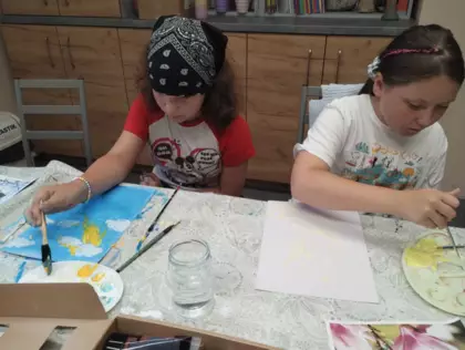 Uczestnicy malują farbami akrylowymi kwiaty.